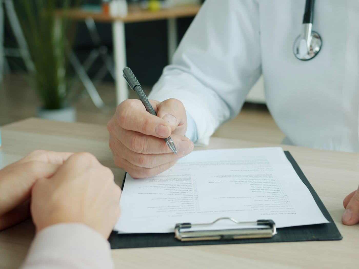 Médecin remplissant un formulaire de soins sur le bureau de son cabinet